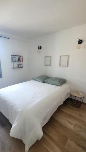 une chambre avec un grand lit blanc dans une pièce dans l'établissement La Gruissanaise, à Gruissan