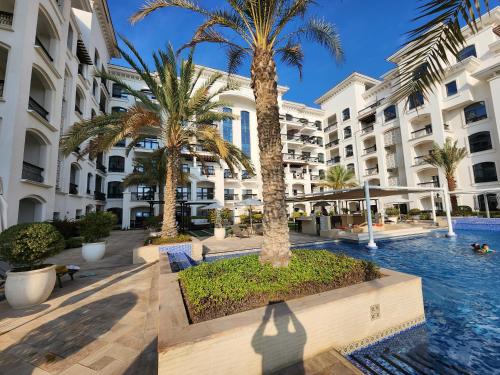 a hotel courtyard with palm trees and a swimming pool at NA HARF108 Stylish Studio - YAS Island in Abu Dhabi