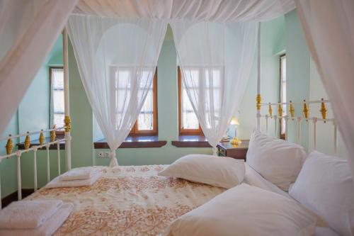 a bedroom with a white canopy bed with white pillows at Palladio Hotel - Portaria in Portaria
