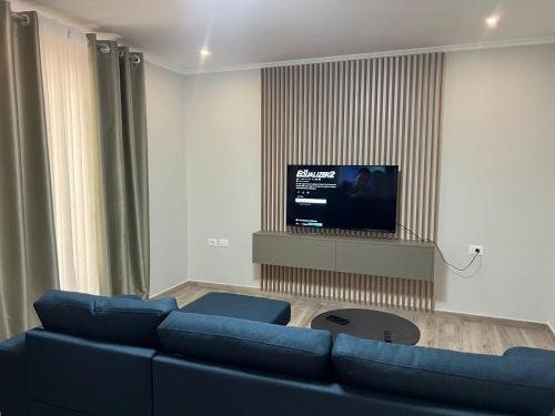 a living room with a blue couch and a flat screen tv at Bulqiza Center Apartment in Bulqizë