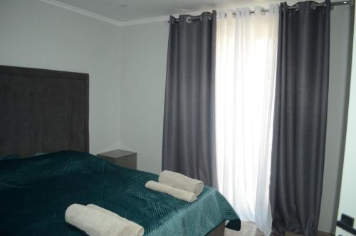 a bedroom with a green bed with two towels on it at Bulqiza Center Apartment in Bulqizë