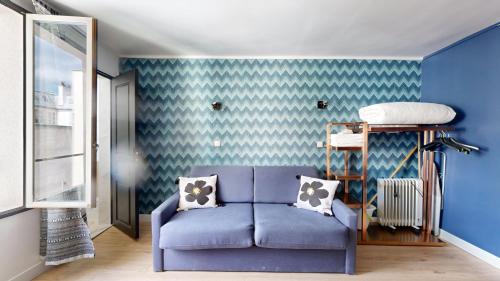un salon avec un canapé bleu et un mur bleu dans l'établissement Bluestay 11 - Charmant Studio au Cœur de Paris, à Paris