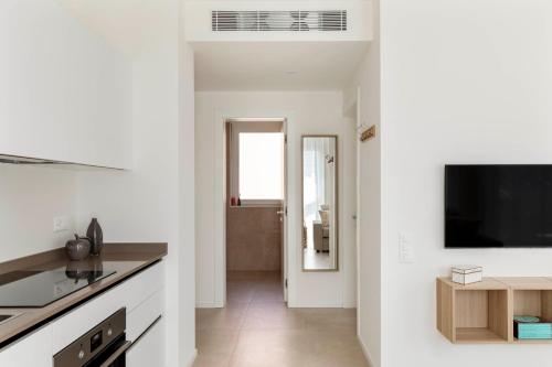 a kitchen with white walls and a flat screen tv at Regalia Suites - Free Parking in Lugano