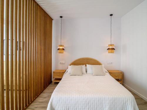 een slaapkamer met een bed met witte lakens en 2 lampen bij Antonella Suites in Fuentes de Andalucía