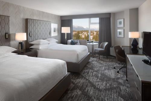 a hotel room with two beds and a television at Sheraton Vancouver Guildford Hotel in Surrey