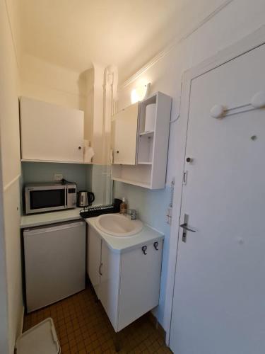 une petite cuisine avec un évier et un micro-ondes dans l'établissement chez Joseph, à Ville-dʼAvray