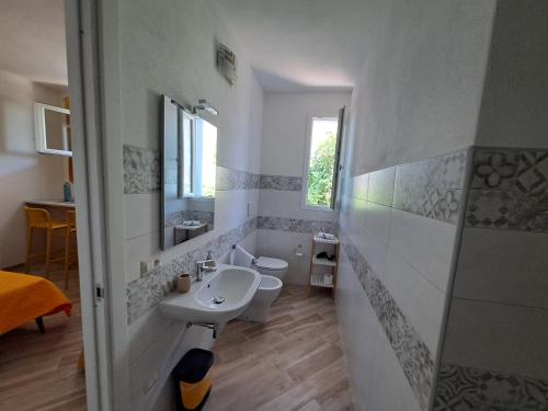 a white bathroom with a sink and a toilet at I Sette Ulivi Bed and Breakfast in Tergu