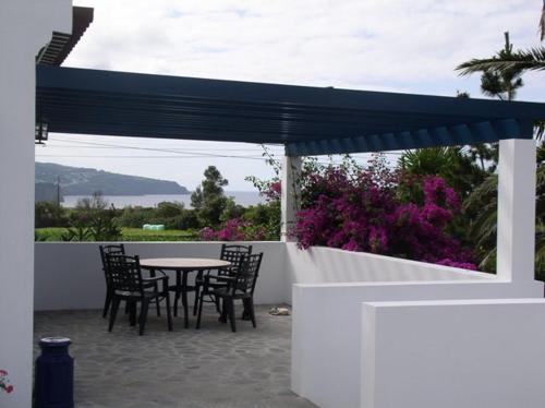 a patio with a table and chairs and a blue umbrella at Quinta dos Afectos in São Vicente Ferreira
