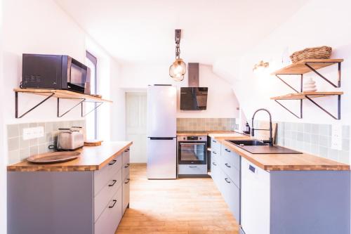 a kitchen with white appliances and wooden counter tops at L'Olivera : entre évasion, sport et nature in Barneville-Carteret