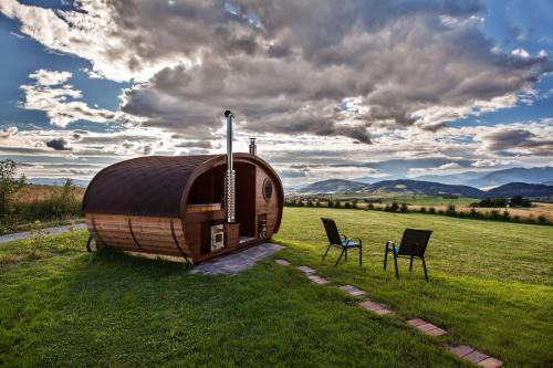 a hobbit house in a field with two chairs at Chalúpka Slnečnica in Brezno
