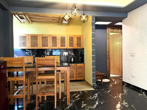 a kitchen with wooden cabinets and a table and chairs at DIVA Nest Kasauli I Luxury Apartment IBalcony I WiFi I Open Air Roof Top Restaurant in Kasauli