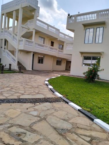 a large white building with a stone walkway in front of it at SHIMBA SPRINGS MBUYU. ( Malindi) in Malindi