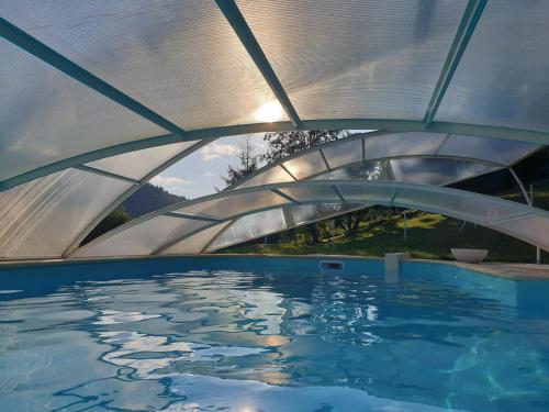une piscine sous un toit métallique avec une piscine dans l'établissement Chalet Bois Cosy - Climatisé - Piscine privée, à Ferdrupt