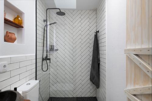 a bathroom with a shower with a white tiled wall at Apartamento Pitaya in Arrecife