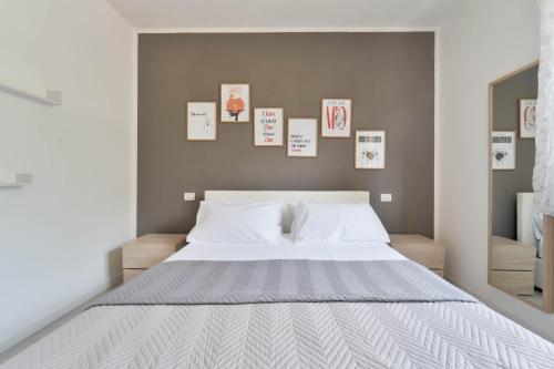 a bedroom with a large white bed with pictures on the wall at Dolce Far Niente Apartment - Lake Como in Colico