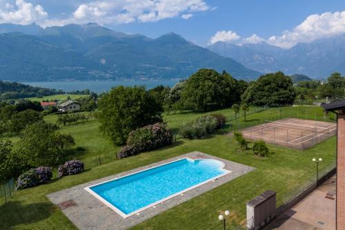 a swimming pool in a yard with a tennis court and mountains at Dolce Far Niente Apartment - Lake Como in Colico