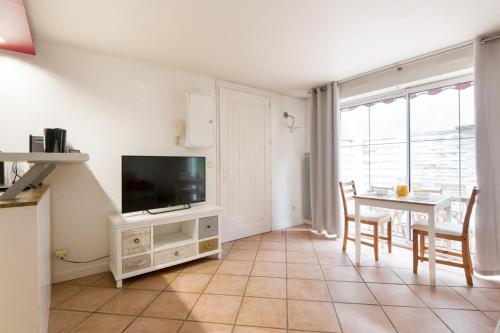 Il comprend un salon doté d'une télévision et d'une table avec des chaises. dans l'établissement Studio avec Terrasse en centre-ville de La Rochelle 3 étoiles, à La Rochelle
