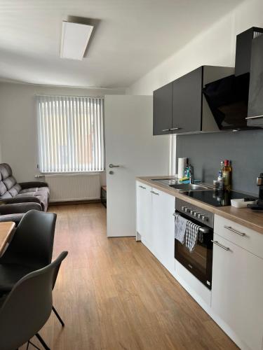 eine Küche mit weißen Schränken und ein Wohnzimmer in der Unterkunft Apartment im Zentrum Trofaiachs - 30 min vom Red Bull Ring in Trofaiach