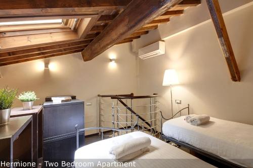 a bedroom with two beds and a dresser and a desk at Calzaiuoli Apartments by Mamo Florence in Florence