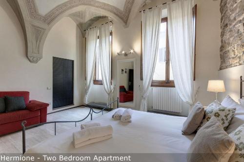 a bedroom with a large white bed and a red couch at Calzaiuoli Apartments by Mamo Florence in Florence