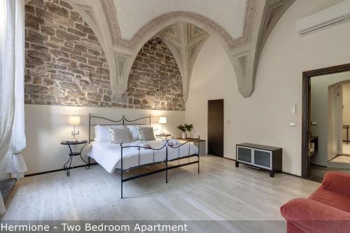 a bedroom with a bed and a brick wall at Calzaiuoli Apartments by Mamo Florence in Florence