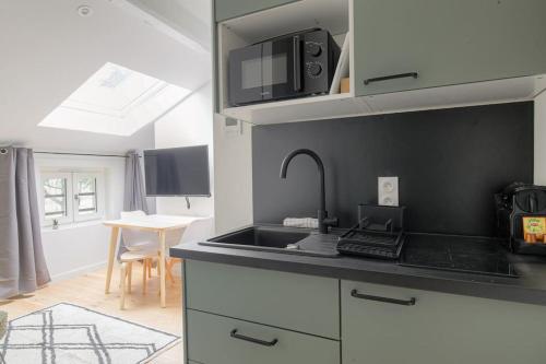 une cuisine avec un évier et un micro-ondes dans l'établissement Studio neuf, clim et parking, Cité Internationale, à Caluire-et-Cuire