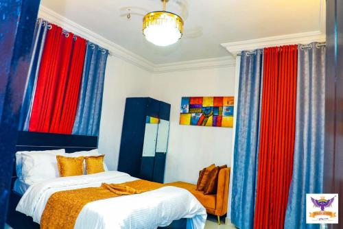 a bedroom with two beds and colorful curtains at Queen Esther's Luxury Apartment in Ankuru