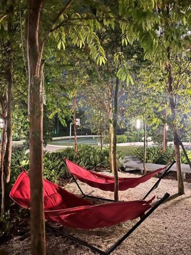 a red hammock in the middle of trees at Mus lim Homestay Gaia Residence, Rawang in Rawang