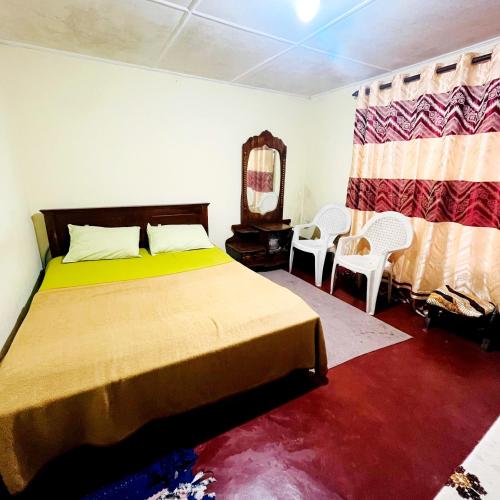 a bedroom with a bed and a mirror and chairs at Haranya Homestay in Hatton