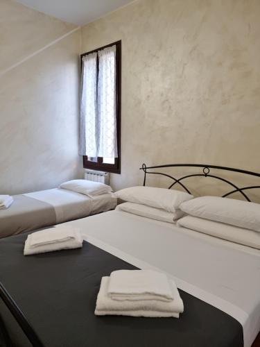 two beds in a room with towels on a table at Rialto House in Venice