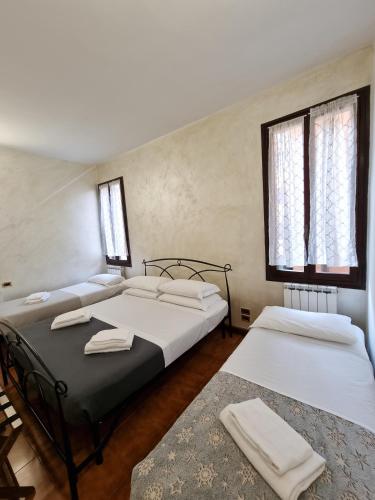 two beds in a room with two windows at Rialto House in Venice