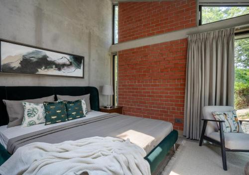 a bedroom with a bed and a brick wall at LohonoStays Villa Amani 8A in Coonoor