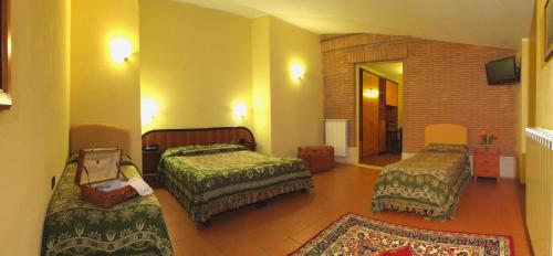 a hotel room with three beds and a television at LH Albergo il Picchio in Pescasseroli