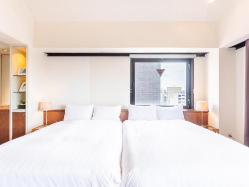 two white beds in a room with a window at Tabist Urban Stays Asakusa in Tokyo