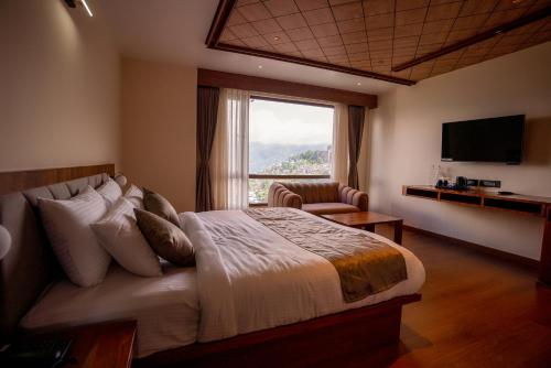 a bedroom with a large bed and a large window at Evara Hills, Gangtok in Gangtok