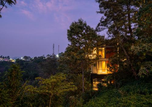 a house in the woods with its lights on at LohonoStays Villa Amani 8A in Coonoor