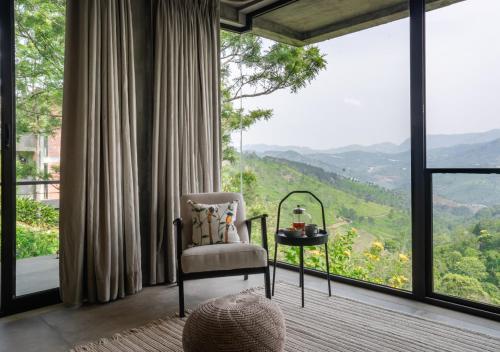 a room with a chair and a table with a view at LohonoStays Villa Amani 8A in Coonoor