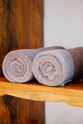 a grey rolled up towel on a wooden shelf at Ysabelle's Inn in El Nido