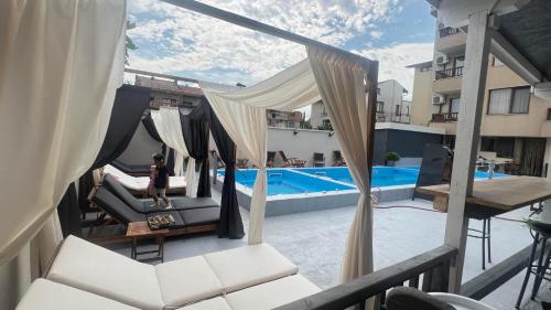 a woman sitting on a chair next to a swimming pool at Family Hotel Malibu in Chernomorets