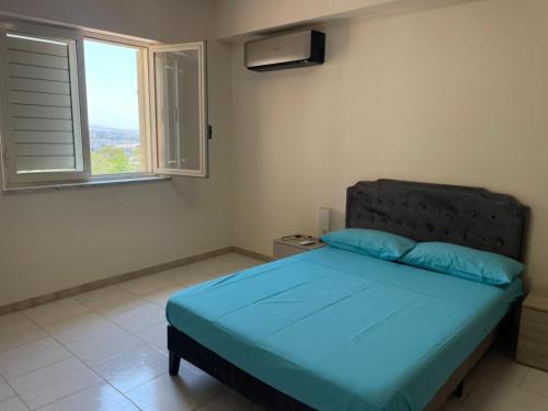 a bedroom with a bed with blue pillows and a window at FONDO VERSACE in Reggio di Calabria