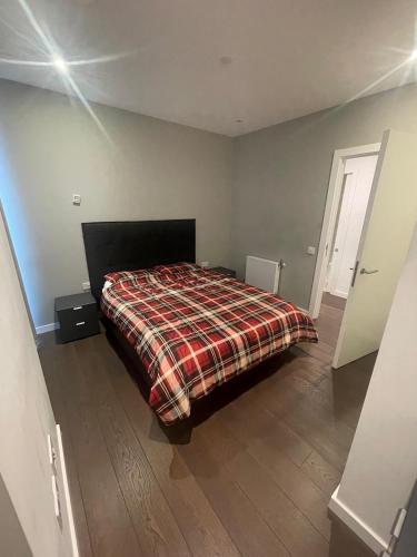 a bedroom with a bed with a plaid blanket at Busco Properties in London