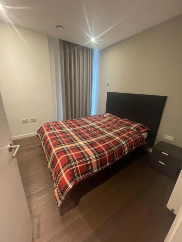 a bedroom with a bed with a plaid blanket at Busco Properties in London