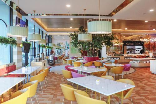a restaurant with white tables and yellow chairs at Leedon Hotel & Suites Surabaya in Surabaya