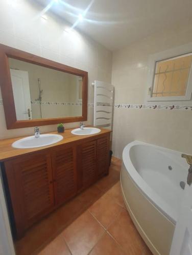 une salle de bain avec deux lavabos, une baignoire et un miroir dans l'établissement Maison proche forêt et Bassin d'Arcachon, à Saint-Jean-dʼIllac