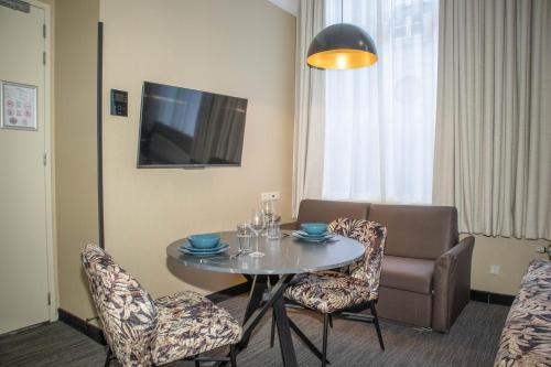 a room with a table and chairs and a television at Golden Mansion Apartment Hotel in Amsterdam