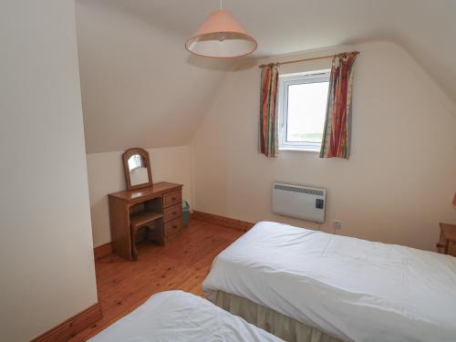a bedroom with two beds and a window and a mirror at No 3 Beach Cottages in Keel
