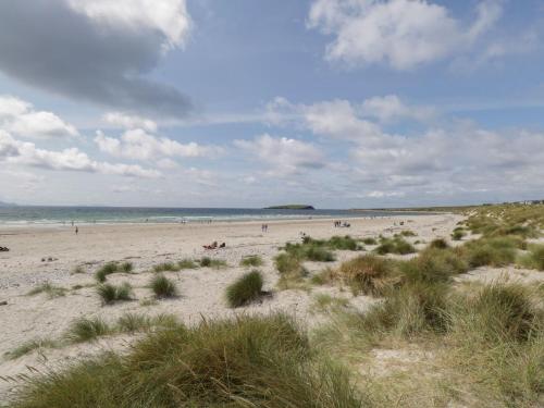 a beach with people on the sand and the ocean at No 5 Beach Cottages in Keel