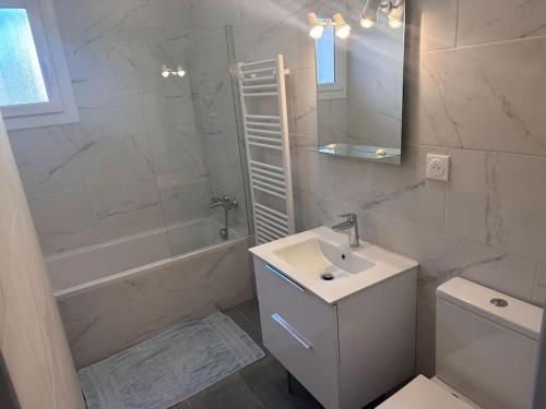 La salle de bains blanche est pourvue d'un lavabo, d'une baignoire et d'un miroir. dans l'établissement A SUARELLA - Villa climatisée - 4 chambres - piscine chauffée, à Sainte-Lucie de Porto-Vecchio