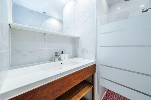 une salle de bain blanche avec un lavabo et un miroir dans l'établissement Appartement Coloré aux portes des Buttes Chaumont, à Paris