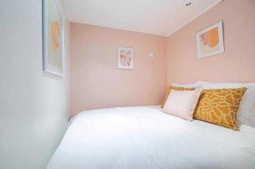 - une chambre avec un lit blanc et deux photos sur le mur dans l'établissement Appartement Coloré aux portes des Buttes Chaumont, à Paris